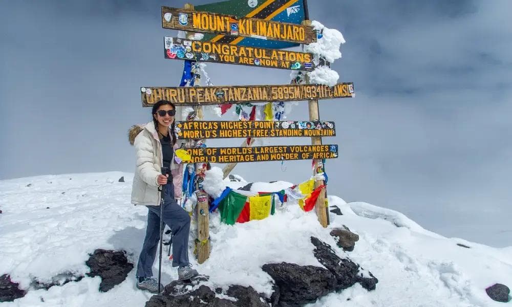 Un grimpeur devant le panneau du sommet Uhuru Peak